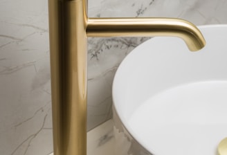 a bathroom sink with a gold faucet next to a white bowl